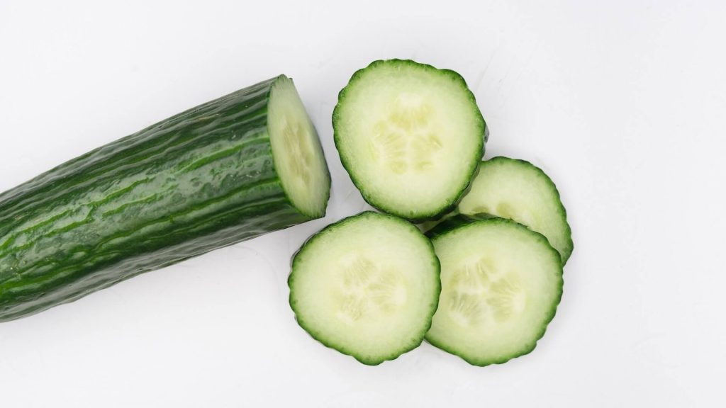 A cucumber with some slices cut up besid it 