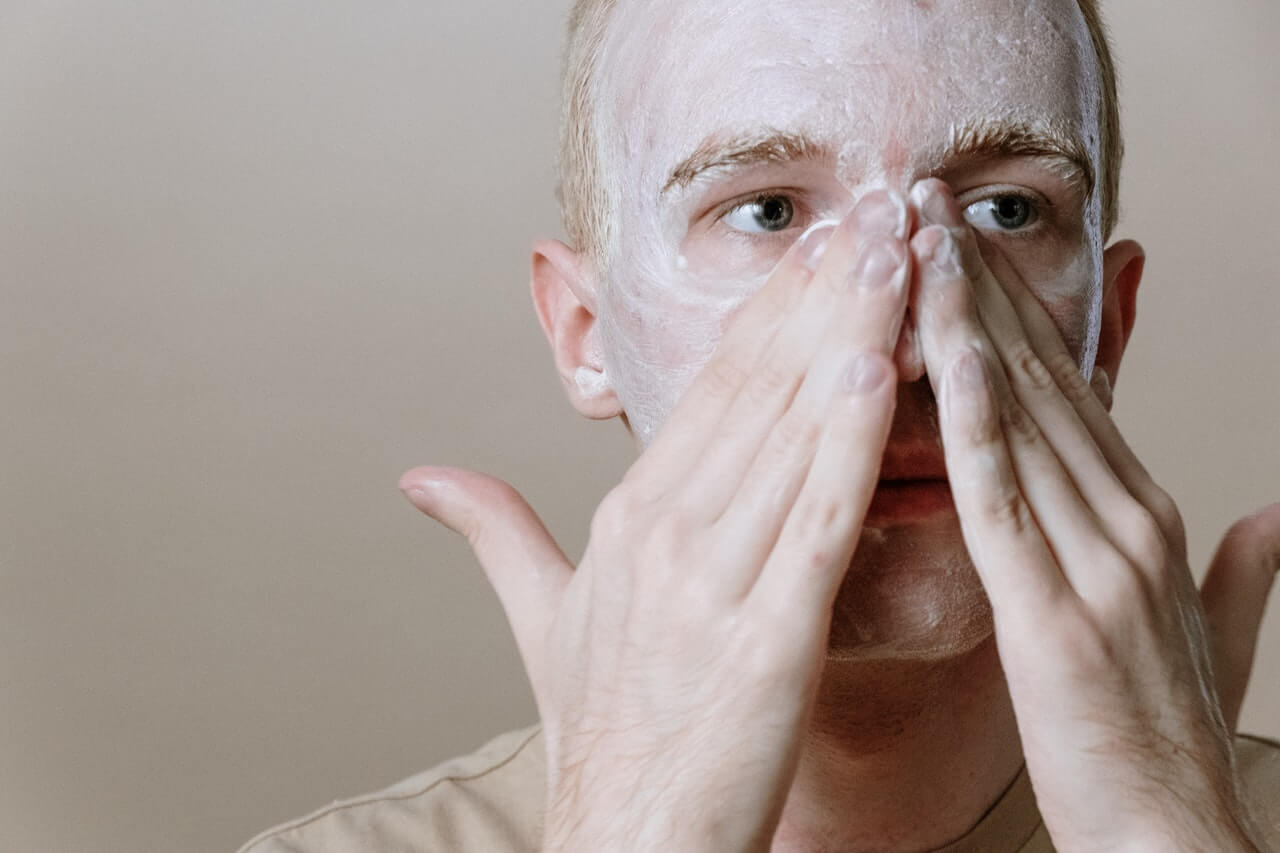 Image of a man washing his face with a cleanser